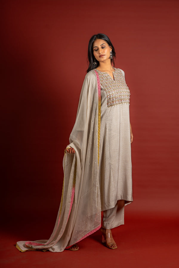 Beige silk top with self-woven butta detailing, with panel and a yoke heavy thread work and sequin embellishments, chiffon dupatta with work and colourful lace detailing, and rayon pant