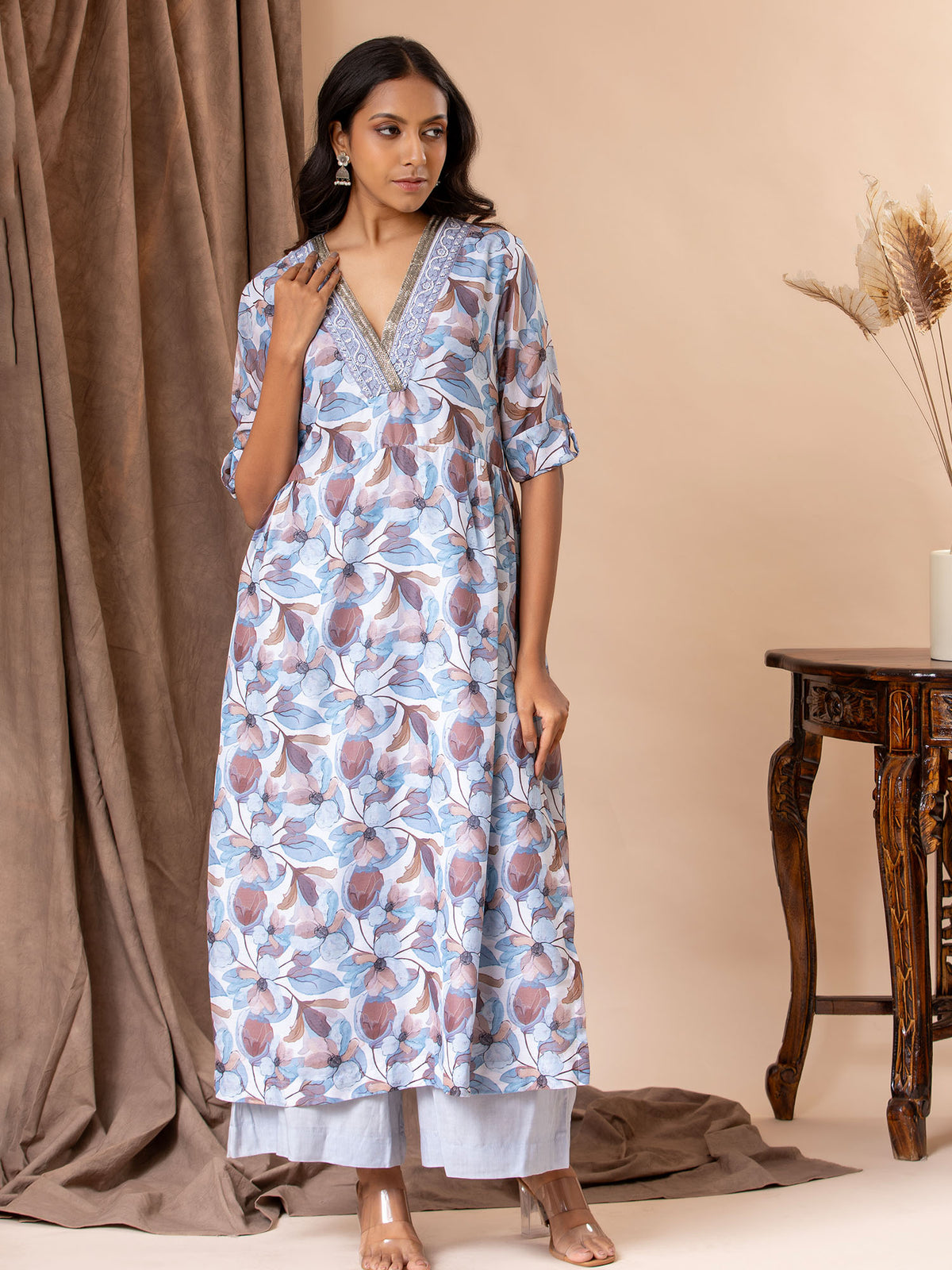 Printed top in shades of blues and browns with cutdana detailing on the neckline, paired with pants.