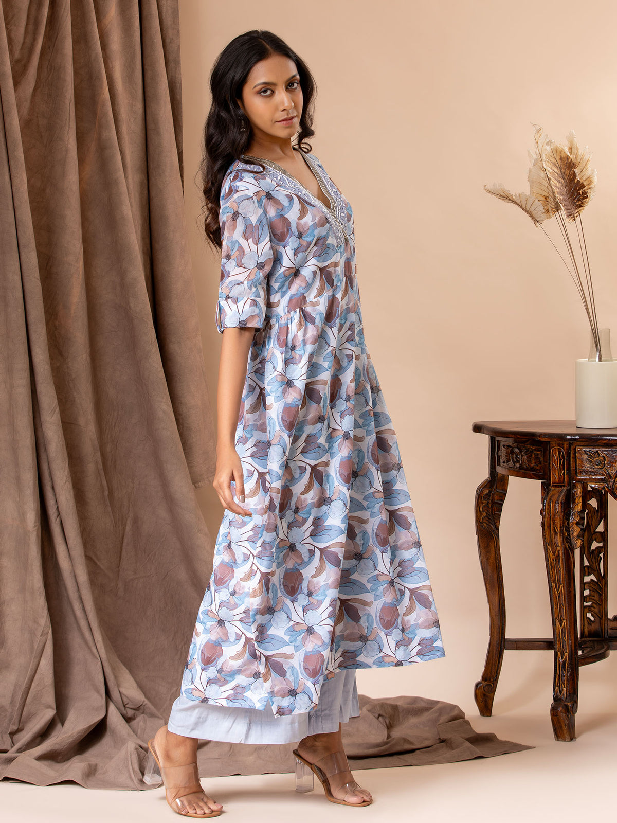 Printed top in shades of blues and browns with cutdana detailing on the neckline, paired with pants.