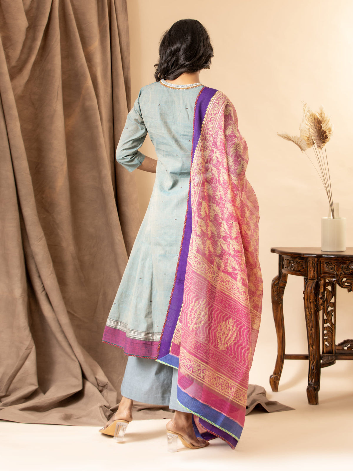 Slate blue handwoven kali top with a pink printed Kota dupatta highlighted with sequins, paired with loose pants. The top features an intricate hand-embroidered neckline