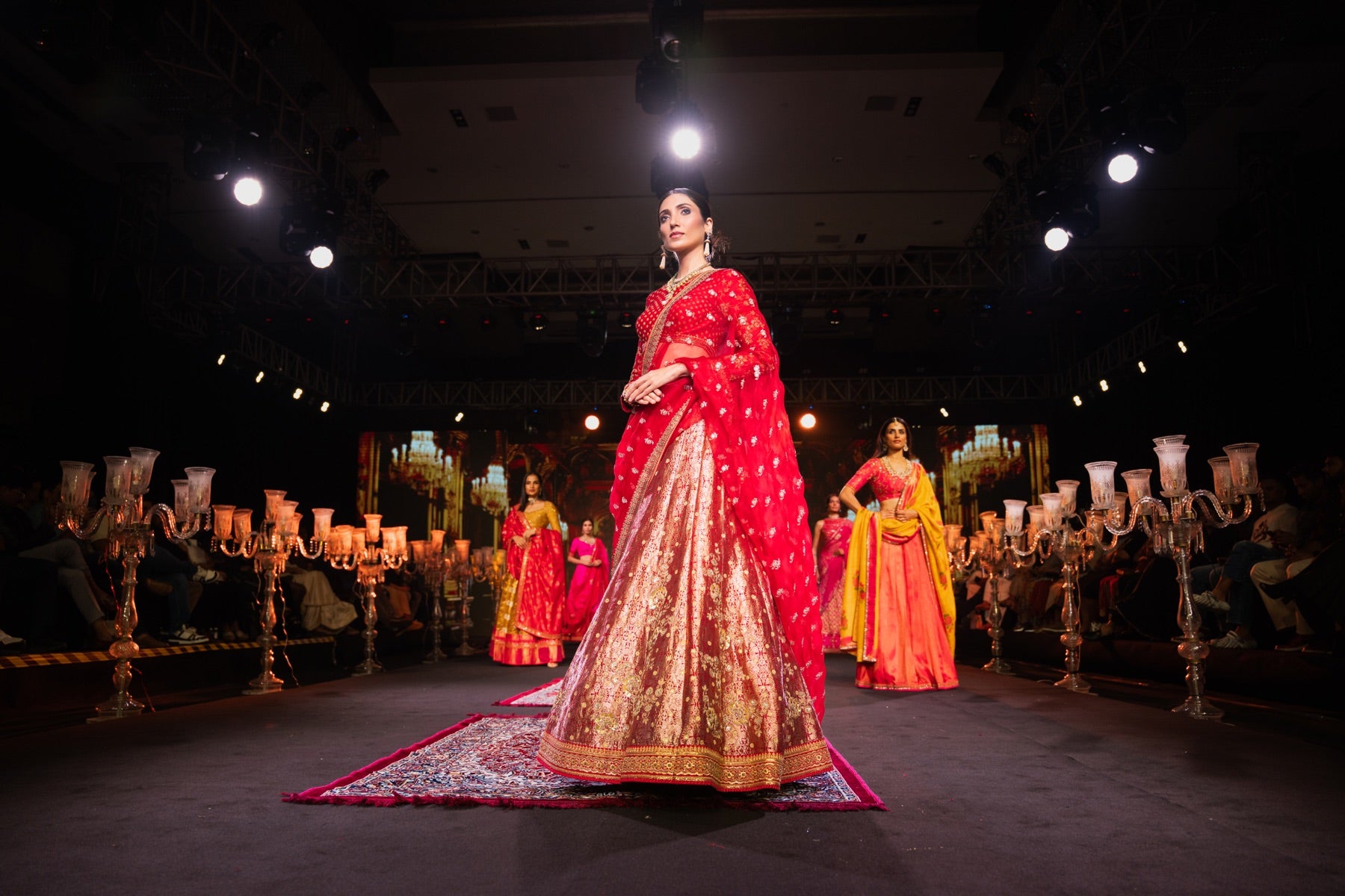 Model in a red and gold bridal lehenga on the runway