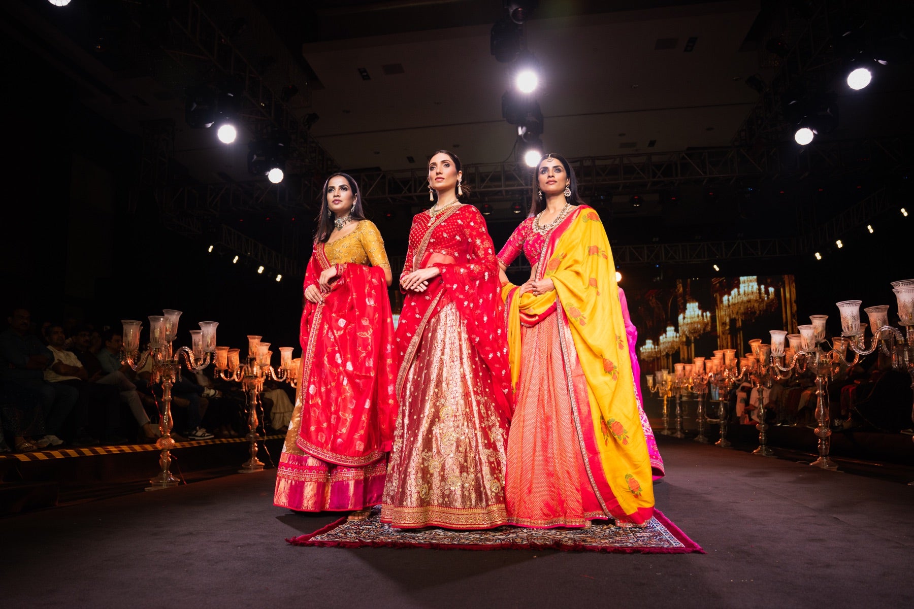 Three models in red, gold, and yellow on the runway